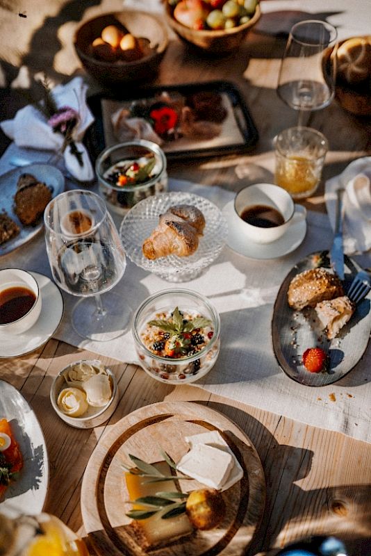 A rustic wooden table with various foods and drinks in glasses and bowls.