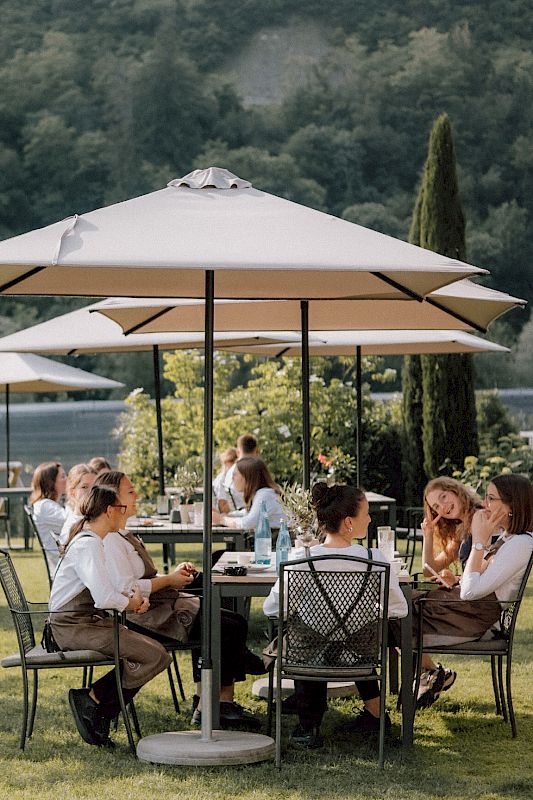 Persone si godono una giornata di sole sotto grandi ombrelloni in un giardino.