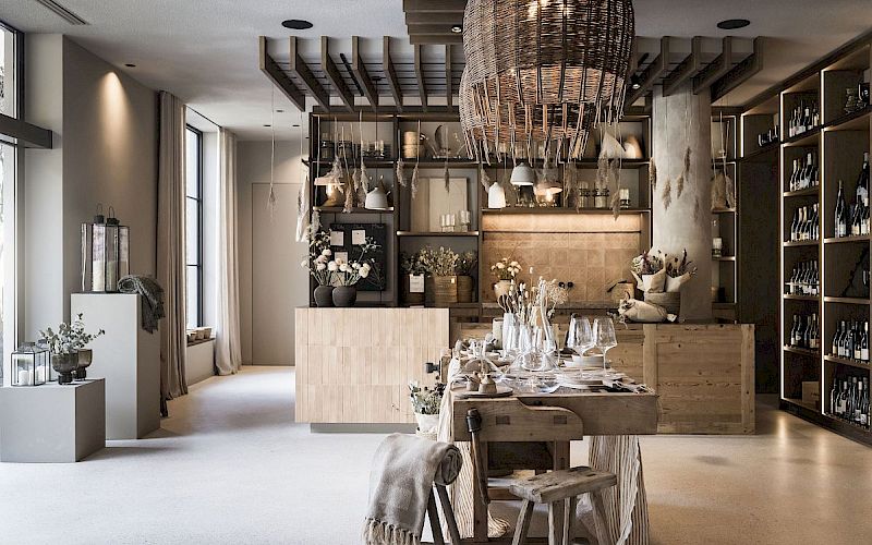 Elegante interni di un ristorante con decorazioni in legno, tavolo apparecchiato e grande lampadario intrecciato.